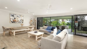 A modern living room with a sofa, coffee table, and a dining area with a bench and chairs. - Barron Heights in Caravonica (Cairns)