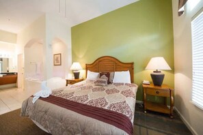 A hotel room with a large bed, two bedside tables with lamps, a wooden headboard, and a green accent wall. - 3Bd Resort 3 Miles to Disney (Orlando)