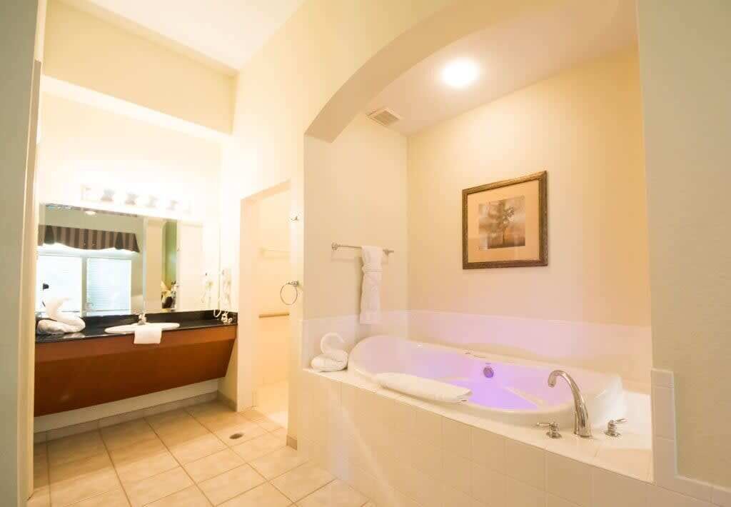 A modern bathroom with a large bathtub, a separate sink area, and a framed picture on the wall.