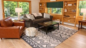 A cozy cabin interior with a leather sofa, a coffee table, and a patterned rug.