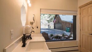 A bathroom with a large window, a sink, and a mirror.