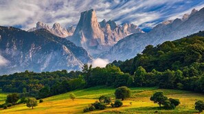 A mountainous landscape with a prominent peak, lush greenery, and a clear sky.