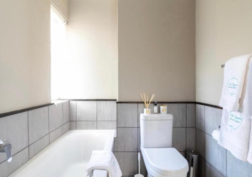 A modern bathroom with a bathtub, toilet, and towel rack.