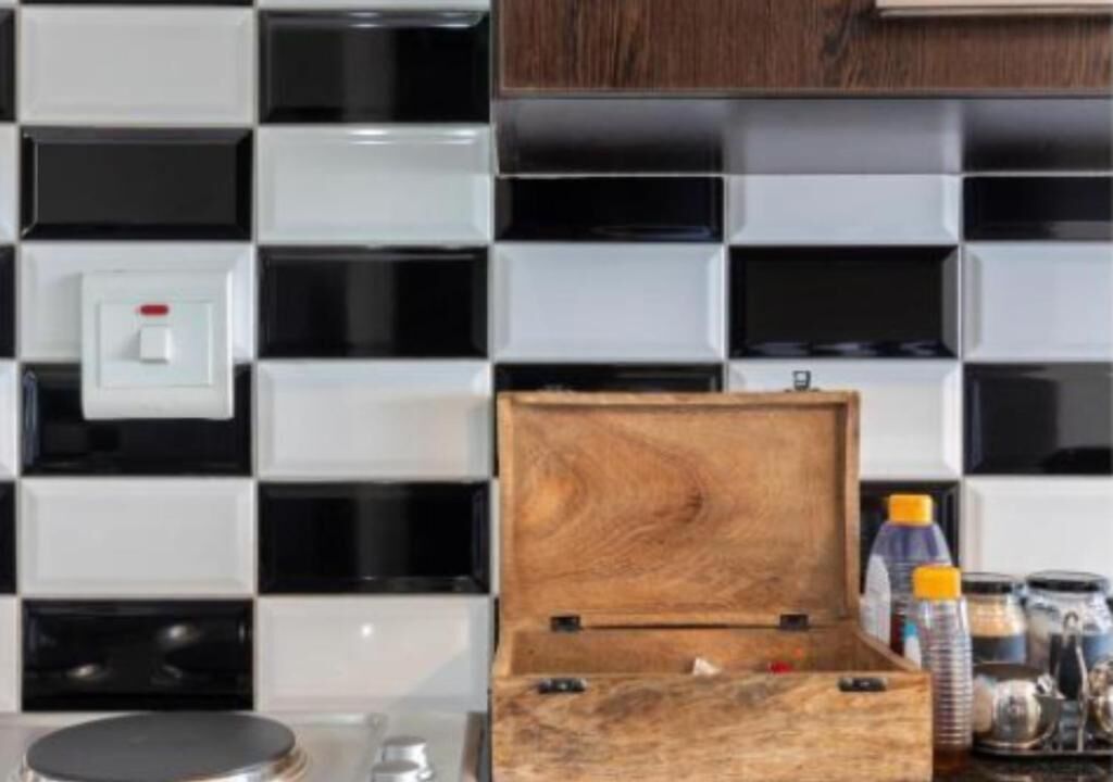 A kitchen with a checkered backsplash, a wooden box on the counter, and various kitchen items.