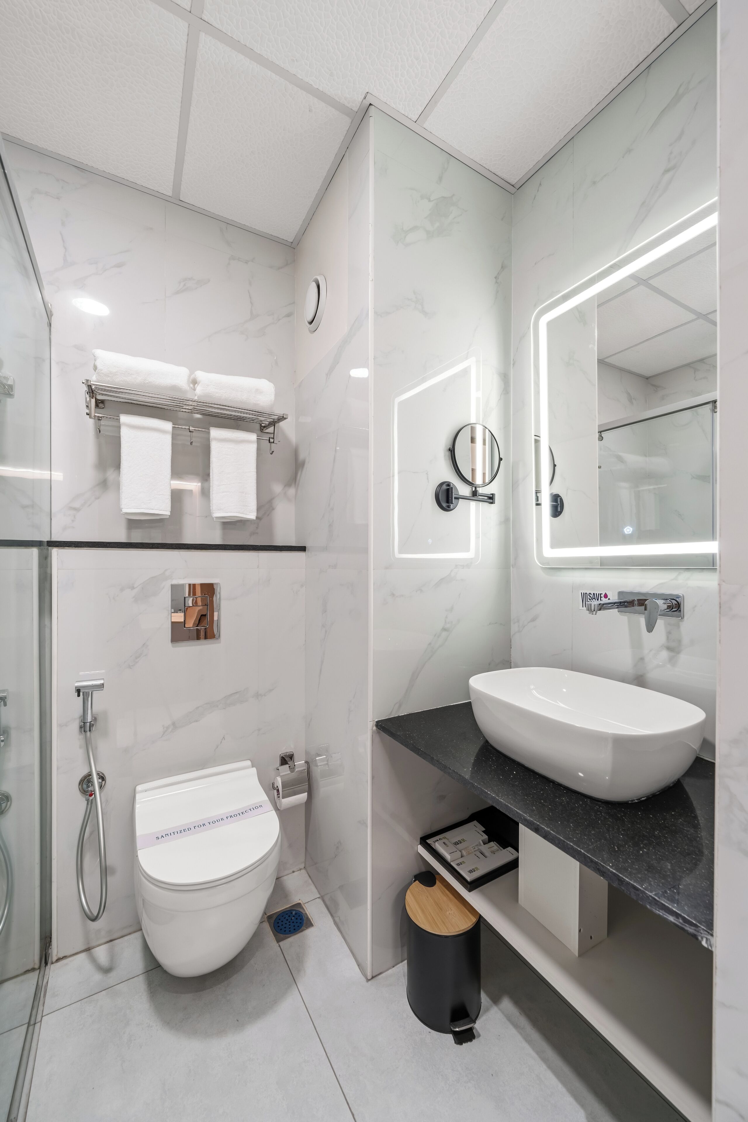 Een moderne badkamer met een wit toilet, een grote spiegel en een zwart aanrecht.