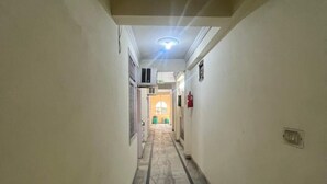 A narrow hallway with a marble floor, white walls, and a ceiling light. - Roomshala Hotel Blue Inn Noida Sector 51 (Noida)