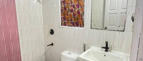 A bathroom with a toilet, sink, shower, and a decorative floral wall piece.