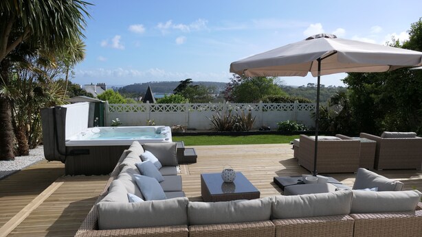 Una terraza de madera con un sofá, un jacuzzi y una sombrilla.