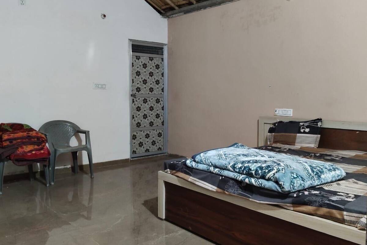Un dormitorio con cama, una silla, un armario y una puerta.