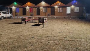 A row of cabins with a grassy lawn in front, each with a small table and chairs. - Fortune Heritage Resort  (Shri Madhopur)