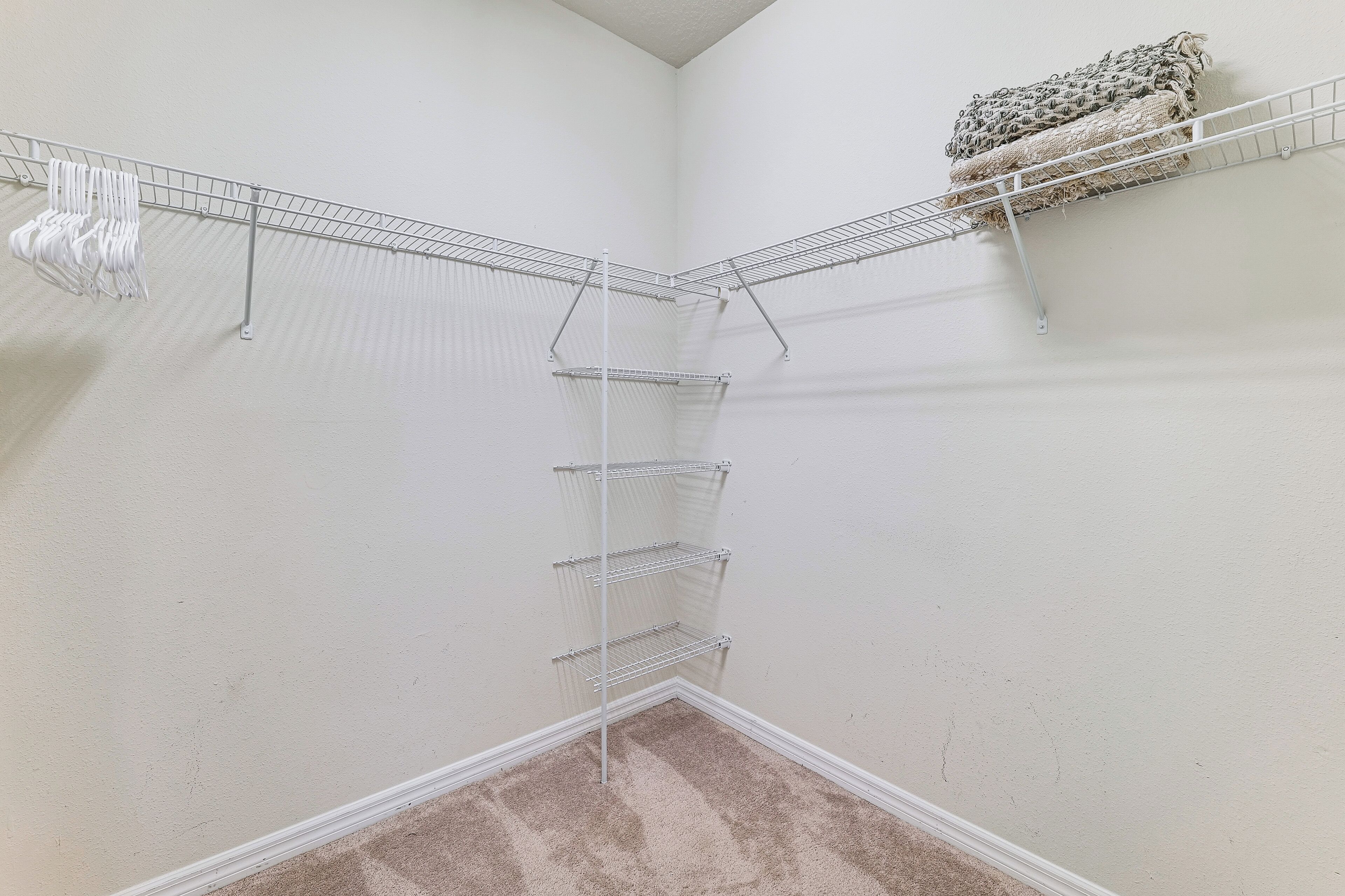 A corner closet with wire shelves and a hanging rack.