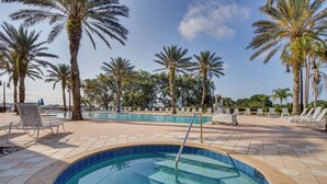 Una piscina con palmeras y sillones de descanso.
