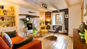 Ein gemütliches Wohnzimmer mit Kamin, Holzboden und verschiedenen dekorativen Gegenständen auf Regalen.
