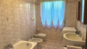 A bathroom with beige tiles, a bathtub, a bidet, a toilet, and a sink. - La Coccinella Apartment with Better Sleep Technology (Gonars)