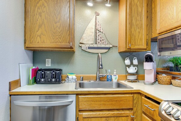 A compact kitchen with wooden cabinets, a stainless steel sink, a toaster, and a microwave. - Relax & Unwind by the Sea! Unit in Ocean Shores (Ocean Shores)