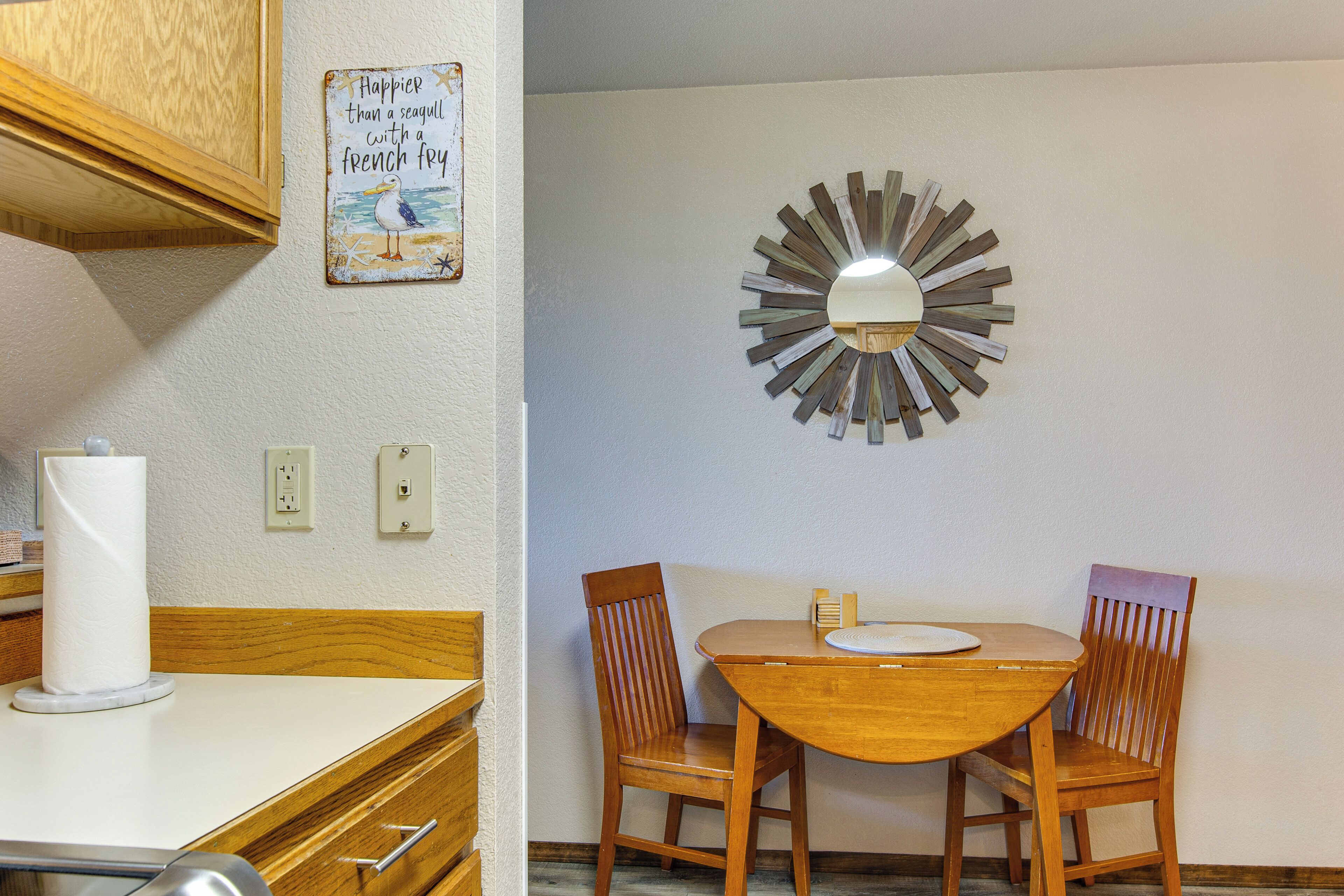 Un coin repas avec une table et des chaises en bois, un miroir décoratif et un panneau fixé au mur.