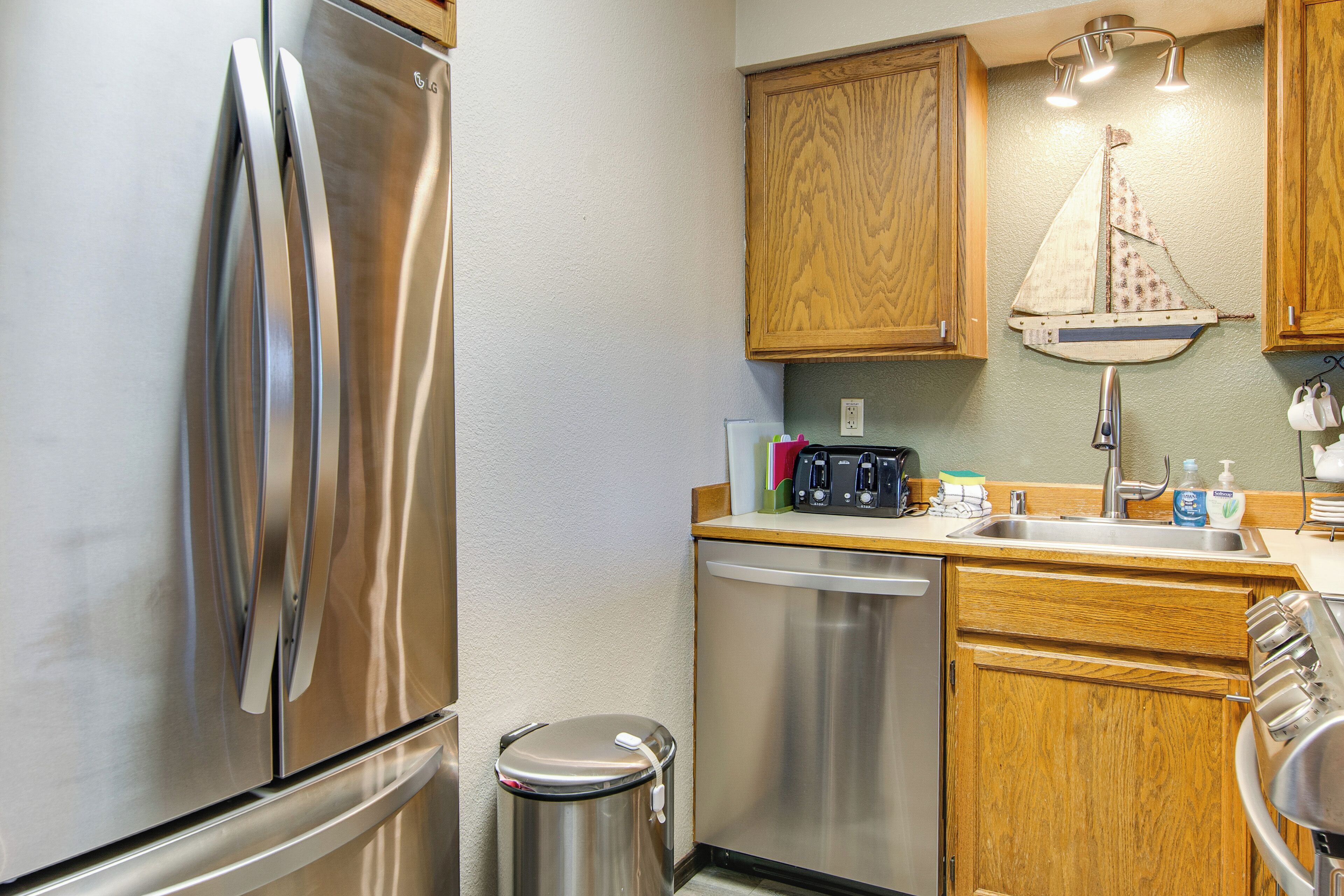 A modern kitchen with stainless steel appliances, wooden cabinets, and a small sink area.