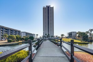 A pedestrian bridge over a canal with a tall building in the background. - Access to Private Beach! Myrtle Beach Resort Condo (Myrtle Beach)