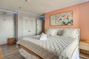 A bedroom with a large bed, a headboard, a wall-mounted painting, and a ceiling light strip. - Access to Private Beach! Myrtle Beach Resort Condo (Myrtle Beach)