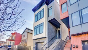 A modern multi-story building with a mix of brick and siding exteriors, large windows, and a visible garage door. - 6 Mi to Manhattan: Luxe Apt w/ City Views! (Jersey City)