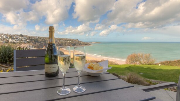 Una bottiglia di champagne, due bicchieri e una ciotola di patatine su un tavolo con vista sulla costa.