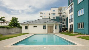 Ein modernes Wohngebäude mit Schwimmbad, kleinem Garten und gepflegtem Rasen.