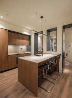 Una cocina moderna con armarios de madera, una isla central con sillas y un espejo grande.