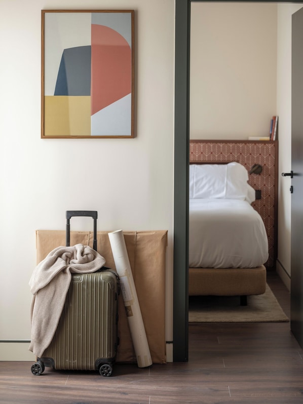 A room with a bed, a suitcase, and a rolled-up map on the floor. - POSTCODE Chueca (Madrid)