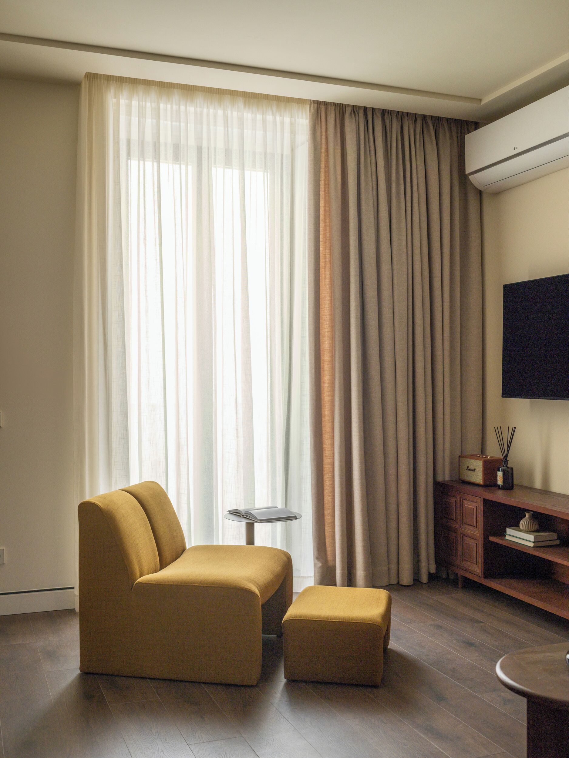 A modern living room with a sofa, ottoman, and a small side table.