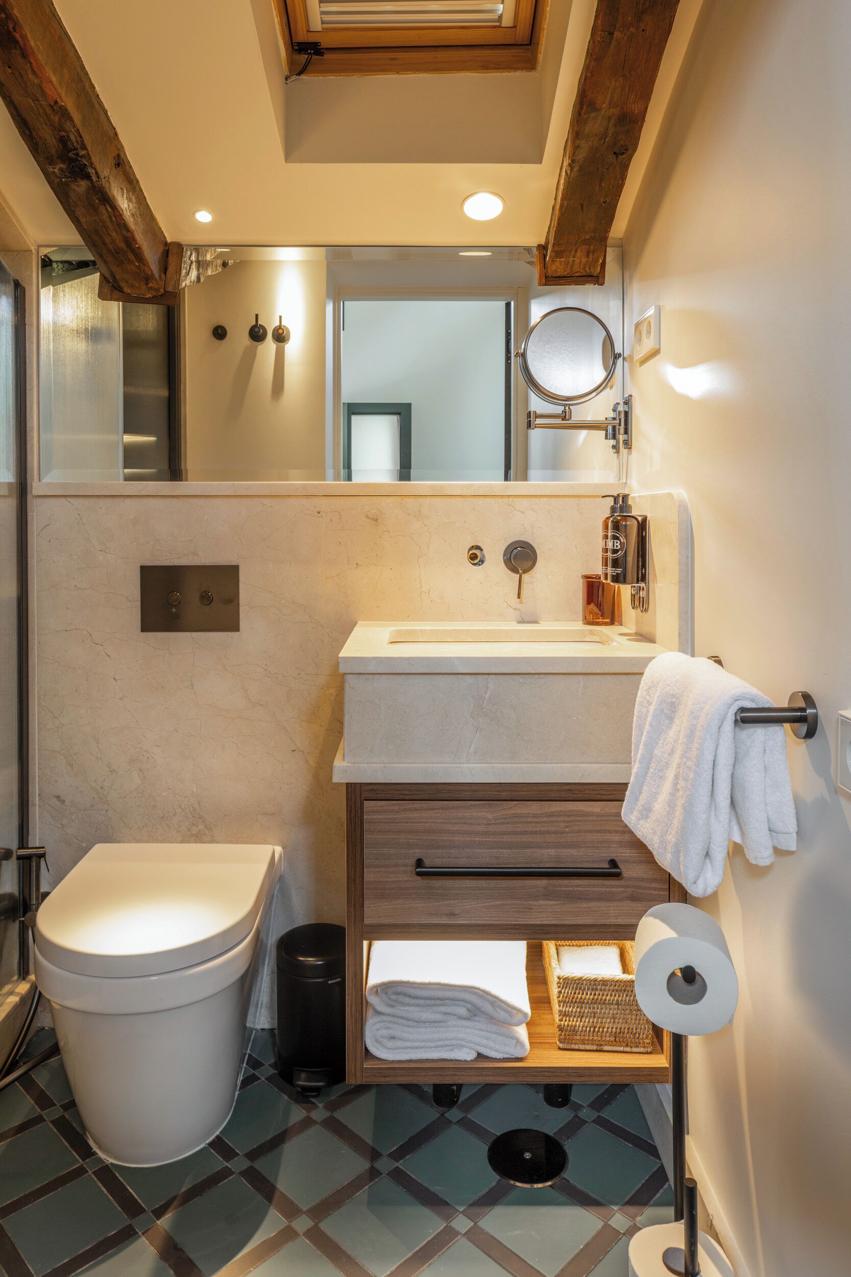 Un baño con inodoro, lavamanos, espejo y toallero.