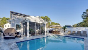Une piscine avec un patio couvert, du mobilier d’extérieur et une vue sur le quartier environnant.