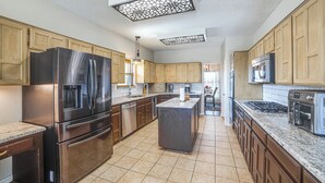 A modern kitchen with stainless steel appliances, wooden cabinets, and a central island. - Walk to Lake! Home w/ Pool Near At&t Stadium (Rowlett)