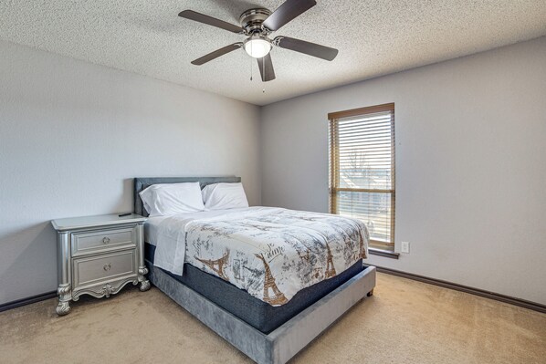 A bedroom with a bed, nightstand, and ceiling fan. - Walk to Lake! Home w/ Pool Near At&t Stadium (Rowlett)