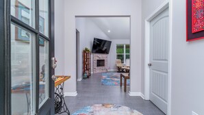 A hallway with a fireplace, a television, and a rug. - Steps to Fairway: Hot Springs Village Golf Retreat (Hot Springs Village)