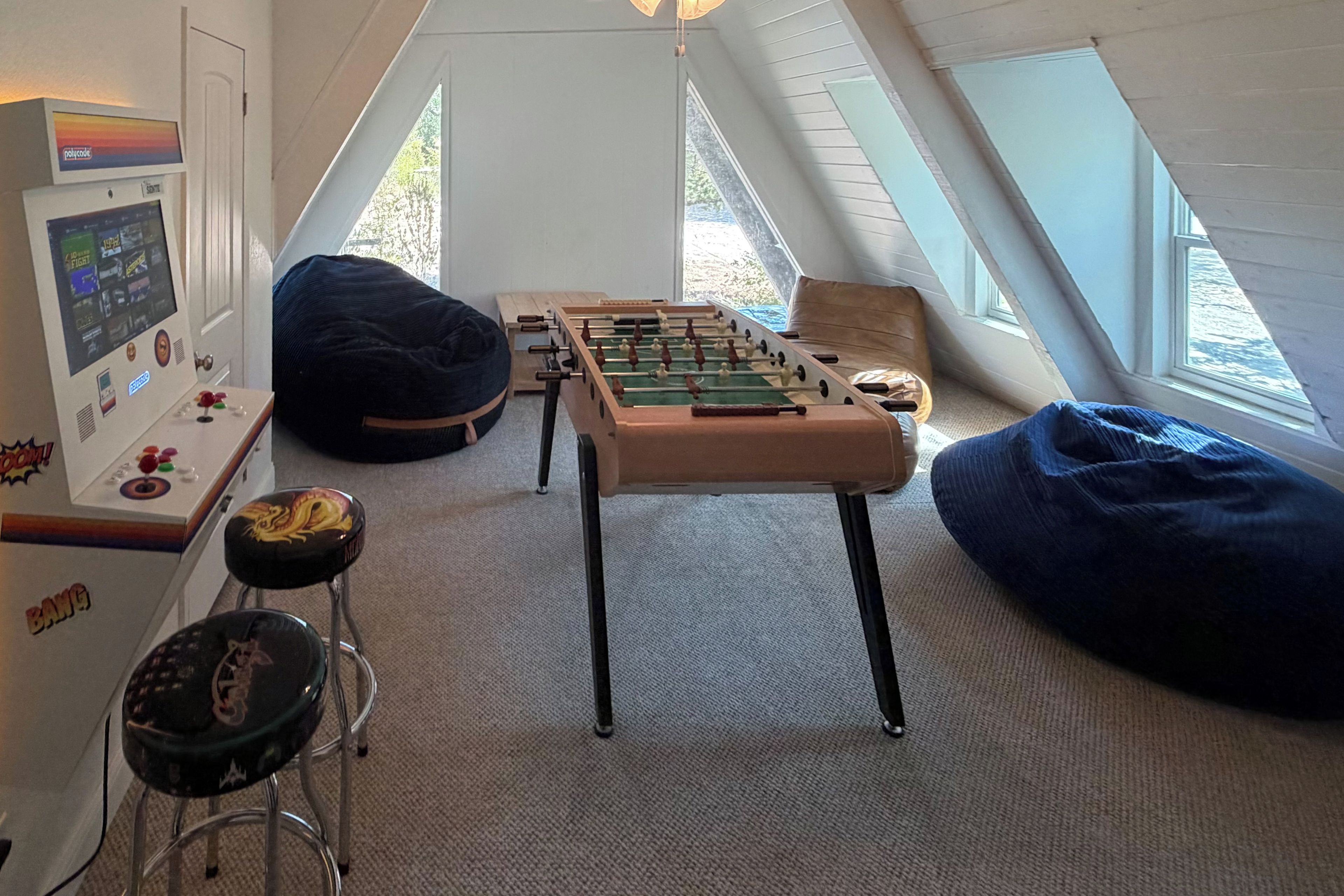 Una habitación acogedora en el ático con mesa de fútbol, consola de videojuegos y sillones de tierno.