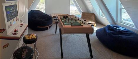 Una habitación acogedora en el ático con mesa de fútbol, consola de videojuegos y sillones de tierno.
