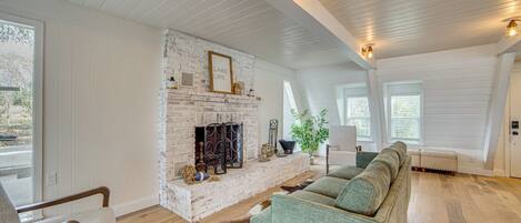A cozy living room with a brick fireplace, wooden floors, and a green sofa.