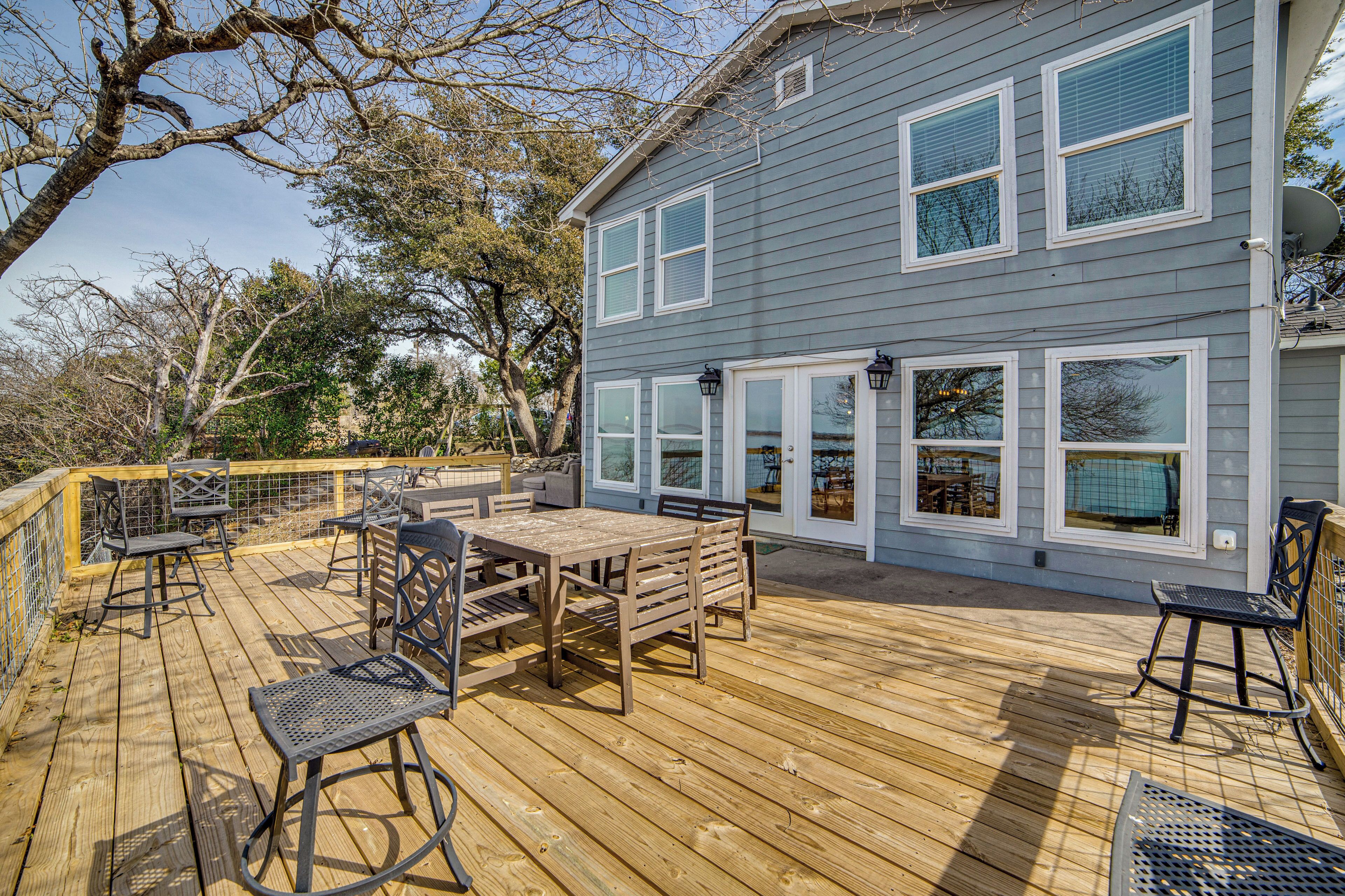 A deck with outdoor furniture, a house with large windows, and a satellite dish.