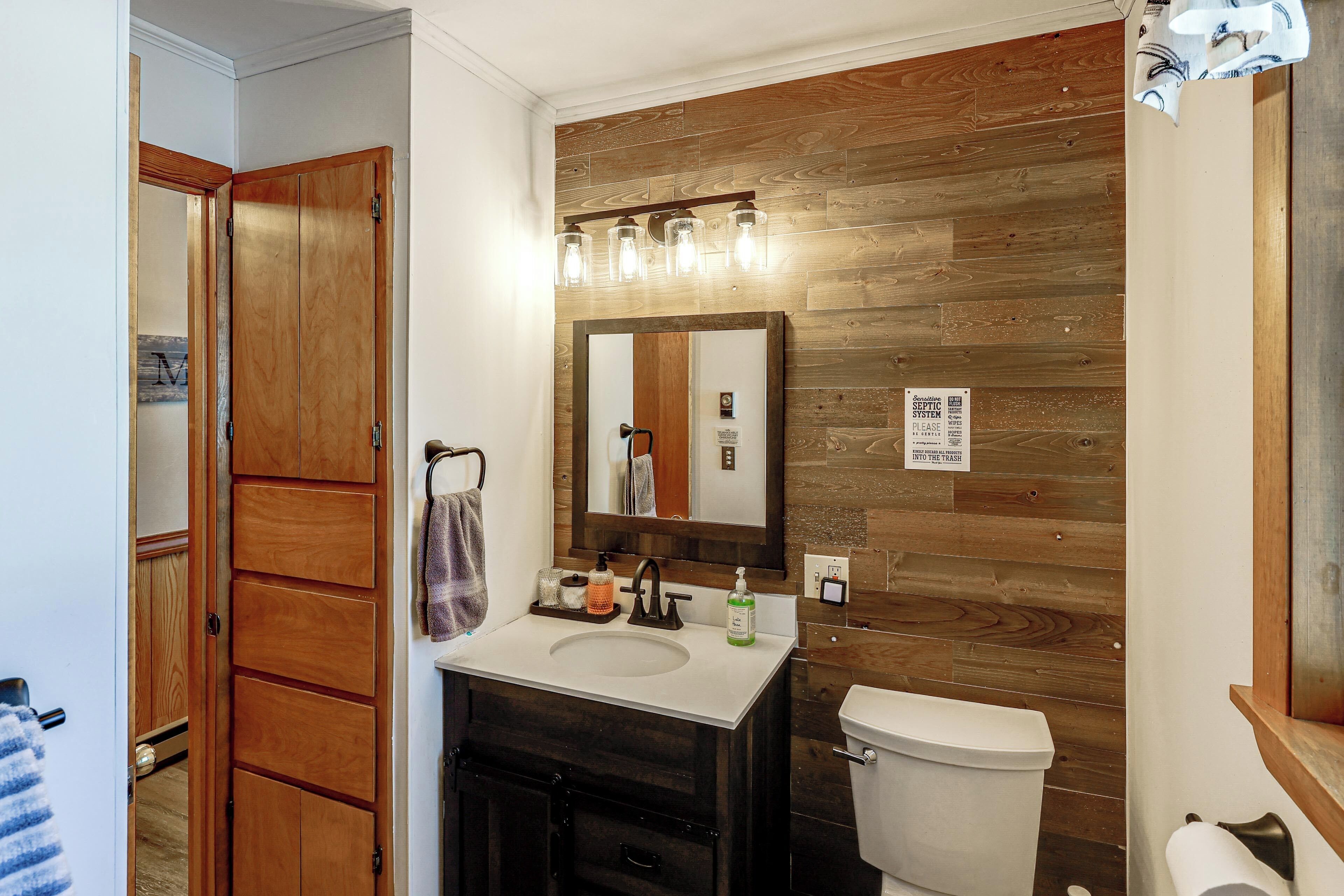 Une salle de bain avec un lambris en bois, un lavabo, un miroir et des toilettes.