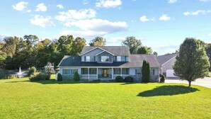 A two-story house with a stone facade, a front porch, and a well-maintained lawn. - Family Home on 9 Acres! Climbing Wall & Gym (Thornville)