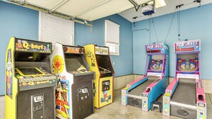 A row of arcade machines in a room with blue walls and a concrete floor. - Family Home on 9 Acres! Climbing Wall & Gym (Thornville)