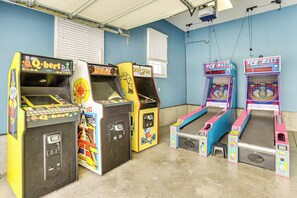 A row of arcade machines in a room with blue walls and a concrete floor. - Family Home on 9 Acres! Climbing Wall & Gym (Thornville)