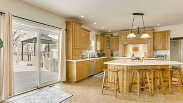 A spacious kitchen with wooden cabinets, a large island with bar stools, and a sliding glass door leading to a patio.