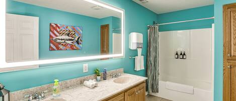 A bathroom with a large mirror, two sinks, a shower, and a towel rack.