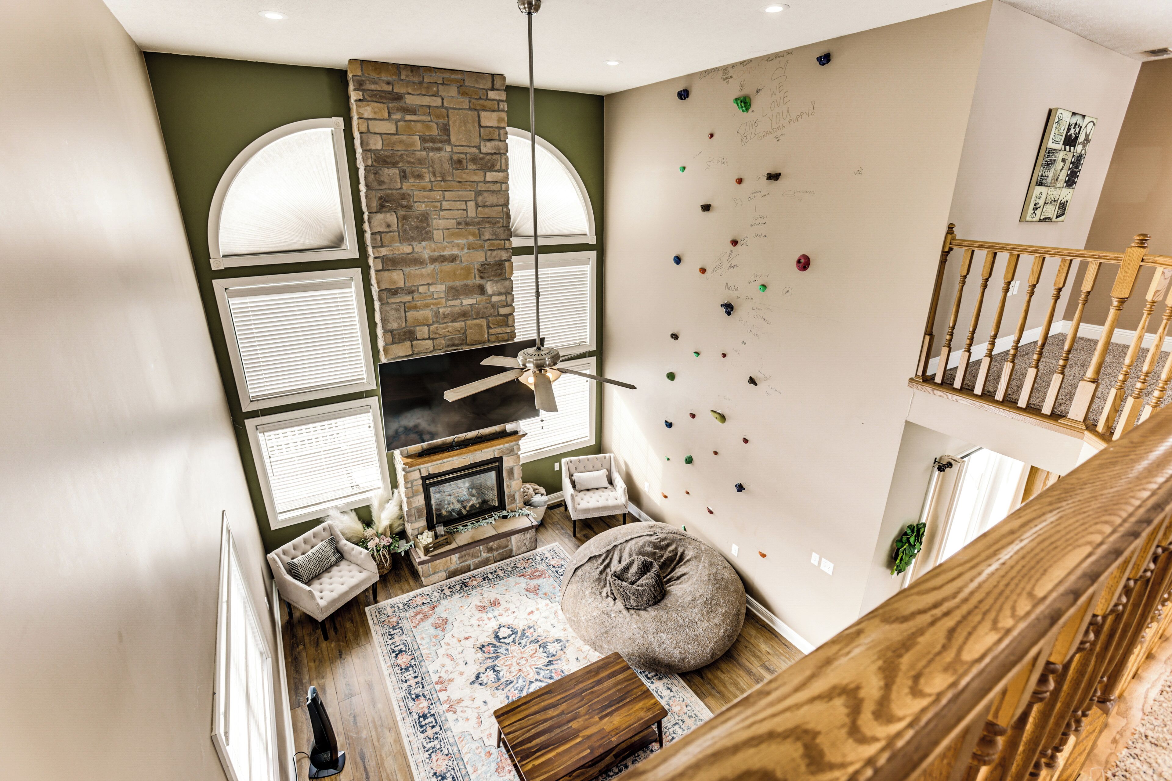 A high-ceiling room with a fireplace, climbing wall, and a staircase.