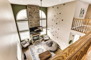 A high-ceiling room with a fireplace, climbing wall, and a staircase. - Family Home on 9 Acres! Climbing Wall & Gym (Thornville)