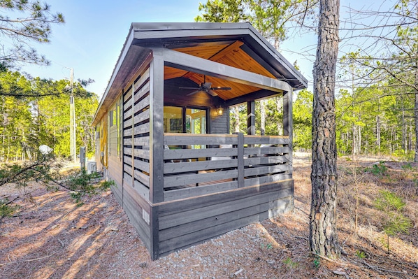 A rustic cabin with a wooden exterior, a balcony, and a ceiling fan.
