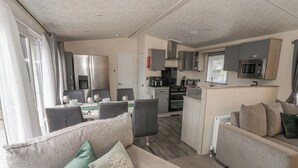 A compact living area with a sofa, a dining table, and a kitchenette. - The Ridgeway (New Quay)