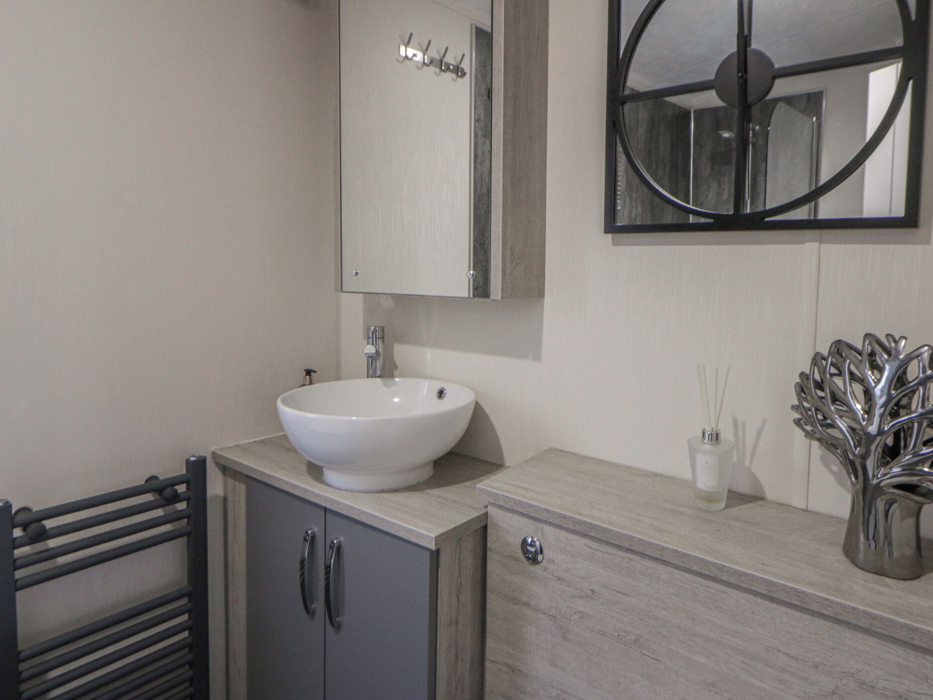A modern bathroom with a white sink, a mirror, and a decorative metal vase.
