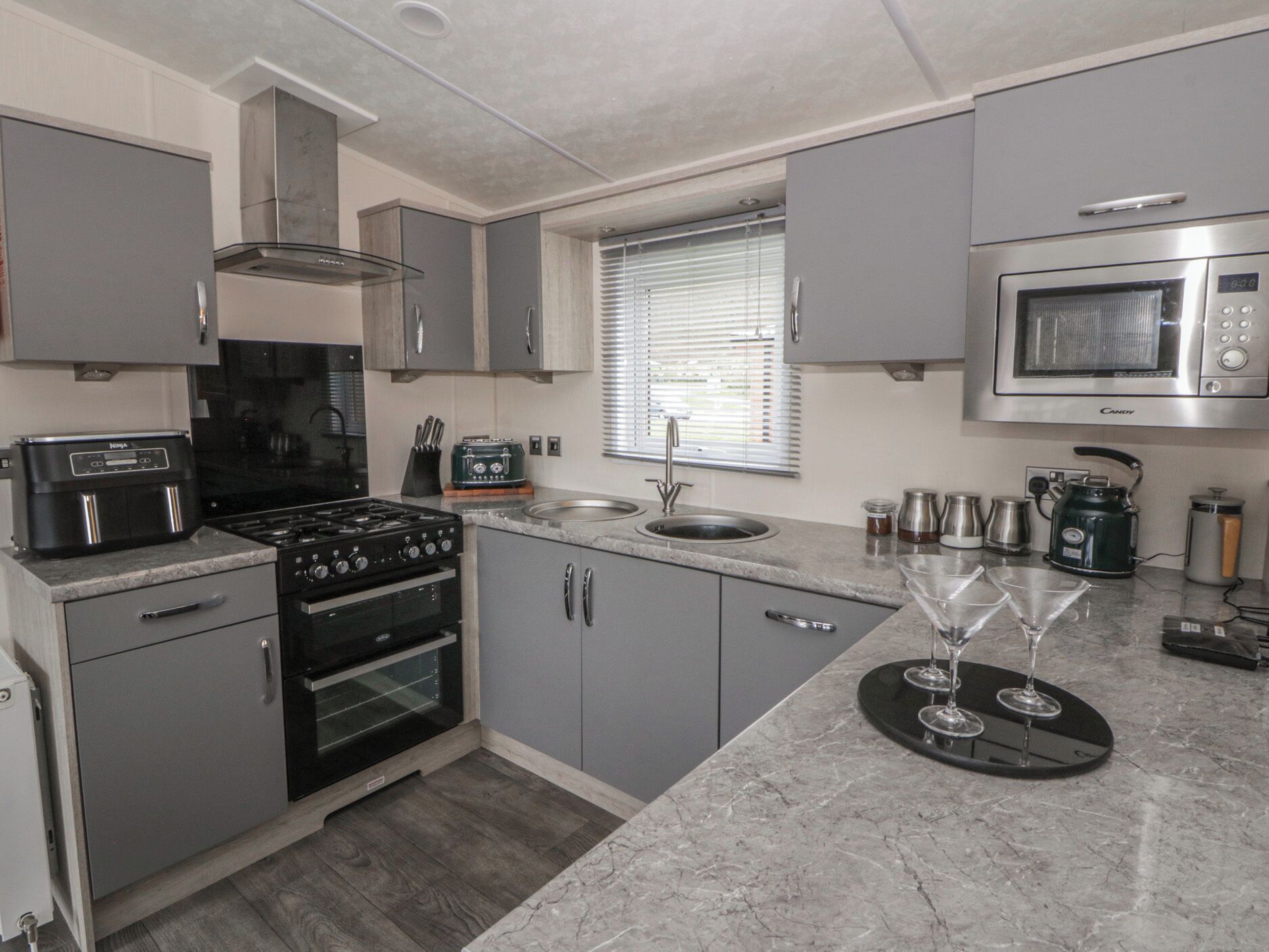 A compact kitchen with grey cabinets, a built-in oven, a microwave, and a coffee maker.